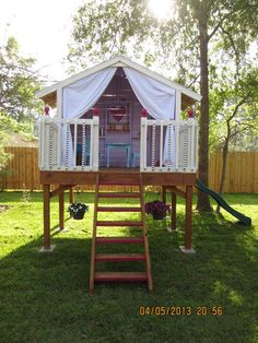 a wooden structure with white curtains on top and stairs leading up to the upper level