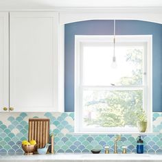 a kitchen with white cabinets and blue backsplashes on the countertops, along with a window