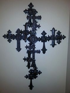 an ornate black metal cross mounted to the side of a wall in a home or office