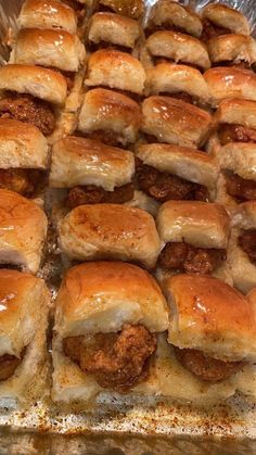 several sausage sliders on tin foil lined up in the shape of mini pigs in a blanket