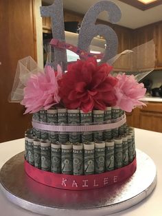 a cake made to look like money with pink flowers on top and the number fifteen