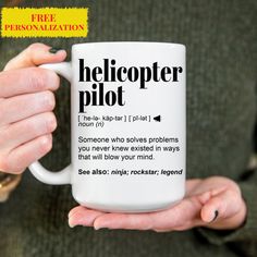 a person holding a coffee mug with the words heliopter pilot on it