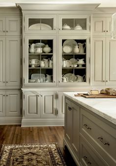 a white kitchen with lots of cabinets and drawers on the wall, along with a rug in front of it