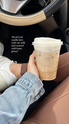 a person holding a cup of coffee in their hand while sitting in the driver's seat