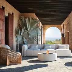 a living room filled with lots of furniture next to a large window covered in plants