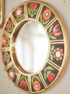 a mirror hanging on the side of a wall next to a hook with flowers painted on it