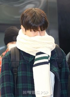 a young man with a scarf around his neck, wearing a green and white sweater