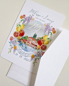 a wedding card with watercolor fruit and flowers on it, next to a white envelope