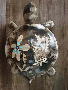 a ceramic turtle with a boat on it's back hanging from a wooden wall