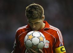 a man holding a soccer ball on top of his chest and looking down at it