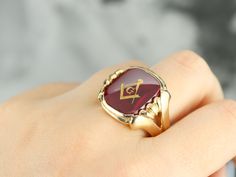 "This large vintage red glass Masonic ring has amazing, yet simply detailed shoulders, rising up from the shank and bending around the corners of the stone. The center is a classic red glass cabochon, inlaid with the gold Masonic symbol, with a nice flat profile. This ring has a substantial feel to it, and makes for a classic Masonic piece! Metal: 14K Yellow Gold Gem: Red Glass Cabochon, Gold Inlaid Masonic Symbol Gem Measures: 16mm x 14mm, Square Cushion Cut Size of Ring: 10 Marks: \"14K\" and Collectible Red Rings With Polished Finish, Classic Red Ruby Jewelry, Heirloom Red Signet Ring With Polished Finish, Classic Red Signet Ring For Formal Occasions, Formal Polished Red Ruby Ring, Formal Red Ruby Ring With Polished Finish, Heirloom Red Ruby Cabochon Ring, Heirloom Red Cabochon Ruby Ring, Classic Red Intaglio Jewelry