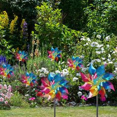 three colorful pinwheels in the middle of a garden