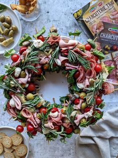 a wreath made out of meats and vegetables on a table with other food items