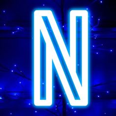 a blue neon sign that reads n in front of a tree with lights on it