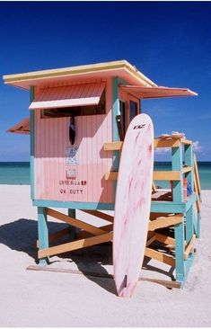 a lifeguard station on the beach with a surfboard leaning against it