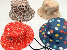 four hats are lined up on a white surface, each with different patterns and colors