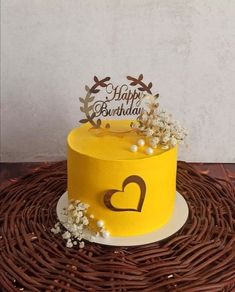 a yellow birthday cake sitting on top of a wicker table