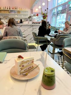 a cake sitting on top of a white table next to a green cup filled with liquid