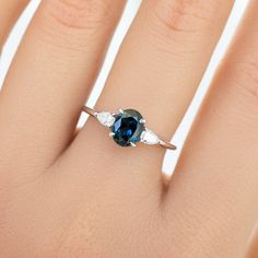 a woman's hand with a blue and white diamond ring on top of it