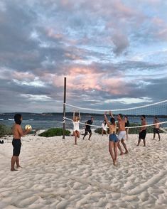 a group of people playing volleyball on the beach