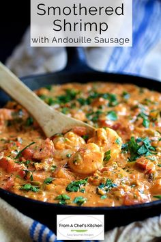 a skillet filled with shrimp and tomato sauce on top of a blue towel next to a wooden spoon