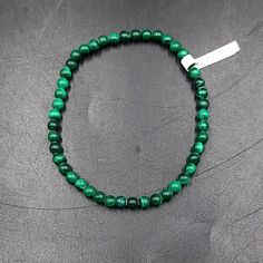 Malachite Bead Bracelet Experience the striking beauty of our Malachite Bead Bracelet, featuring 8mm beads. Malachite is known for its vibrant green hues and distinctive banded patterns, making this bracelet a stunning accessory for any outfit. Each bead is meticulously polished to reveal the stone's natural beauty, creating a bracelet that exudes elegance and sophistication. Harness the Power of Transformation Malachite is celebrated for its powerful transformative and protective energies. Often referred to as the "stone of transformation," malachite helps clear away negative energy and supports emotional healing and growth. Wearing this bracelet can help you harness these transformative powers, bringing balance and positive change into your life. A Gift of Strength and Beauty Our Malachi Emotional Growth, Striking Beauty, 8mm Beads, Green Hues, Worry Stones, Tumbled Stones, Vibrant Green, Positive Change, Emotional Healing