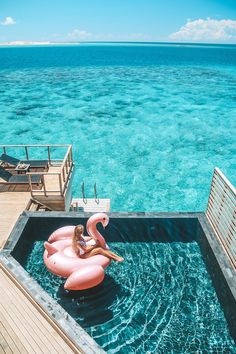 an inflatable flamingo floating on top of the ocean next to a dock