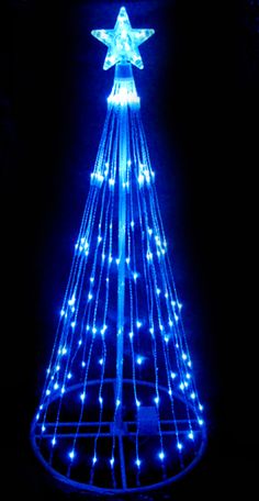 a lit up christmas tree in the dark with blue lights on it's sides