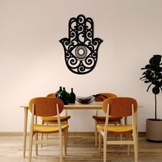 a dining room table with chairs and a hamsa wall decal