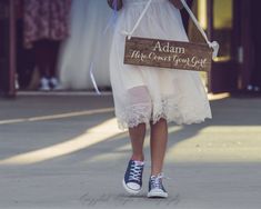 a woman walking down the street holding a sign that says adam the great you got