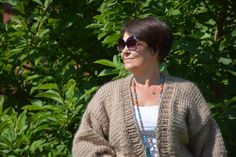 a woman wearing sunglasses standing in front of some bushes