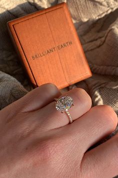 a woman's hand with a ring on it and an orange box in the background