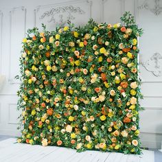 an artificial flower wall in a room with white walls and wood floors, is shown