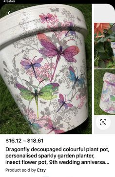 a flower pot with butterflies painted on it sitting in the grass next to some flowers