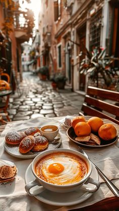 a table topped with donuts and oranges on top of a white plate next to a cup of coffee