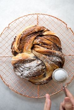 a person is spreading icing on top of a loaf of bread with powdered sugar