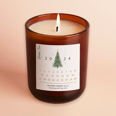 a candle with a calendar on it sitting next to a pink wall and a white background