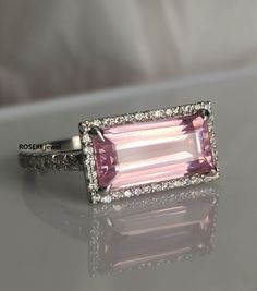 a pink tourmaline and diamond ring sitting on top of a table