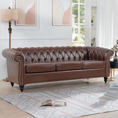 a brown leather couch sitting on top of a rug in a living room next to a window