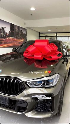 a car with a large red bow on it's hood in a showroom