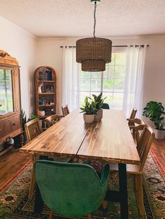 a dining room table with chairs and a potted plant on top of it in front of a window