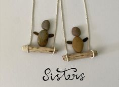 two rocks sitting on top of wooden sticks with the word sisters written below them in black ink