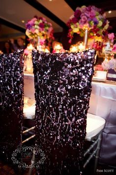 two black sequin bags sitting next to each other on a table with flowers in the background