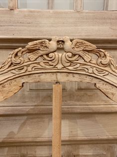 an ornate wooden arch with two birds on it's sides, in front of a building