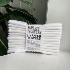 a stack of white towels sitting on top of a table next to a green plant