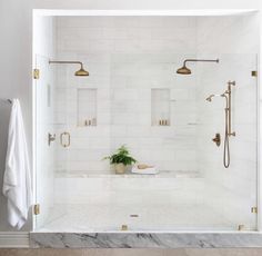 a white bathroom with gold fixtures and marble flooring, including a walk in shower