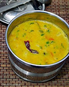 a metal bowl filled with soup on top of a table