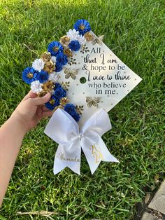 someone is holding up a graduation cap with blue flowers on it and the words, all that i am hope to be those who believe in me