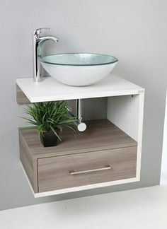 a white sink sitting on top of a wooden cabinet next to a potted plant