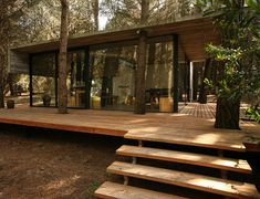 a wooden deck in front of a house surrounded by trees